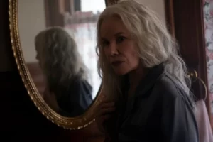 Lady in front of round mirror -'Welcome to the Blumhouse': The Manor
