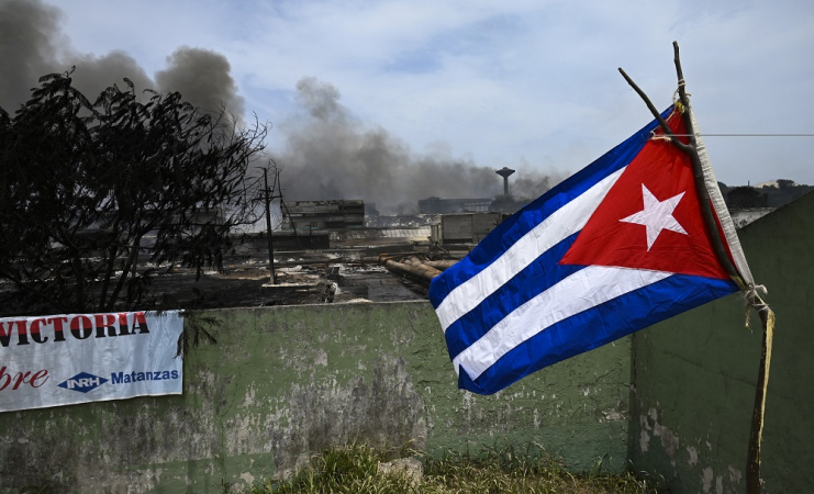 The Cuban flag flies near the destroyed section of the fuel depot, which was engulfed in flames for five days after lightning struck one of its tanks.